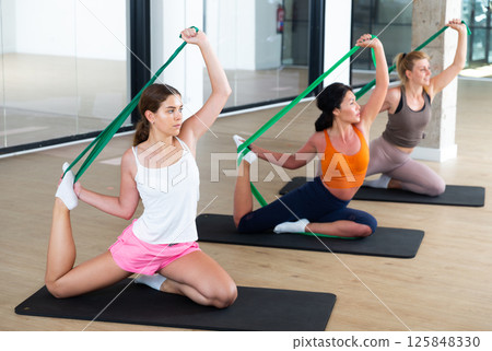 Women are doing stretching exercise with green resistance bands. Teamwork, good mood and healthy lifestyle concept Women are doing stretching exercise with green resistance bands. Teamwork, good mood and healthy lifestyle concept 125848330
