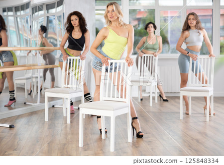 Slender women rehearse modern dances using chair Slender women rehearse modern dances using chair 125848334