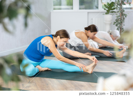 Young woman practicing stretching exercises in yoga studio Young woman practicing stretching exercises in yoga studio 125848355