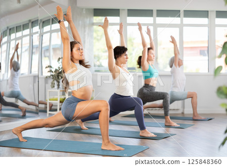 Young female yoga enthusiast performing Virabhadrasana in studio 125848360