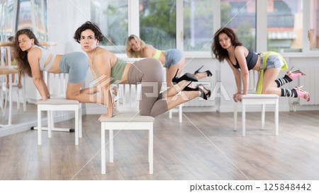 Female dancers wearing high heels shoes stretching legs while practicing in studio before dance performance providing Female dancers wearing high heels shoes stretching legs while practicing in studio before dance performance providing 125848442