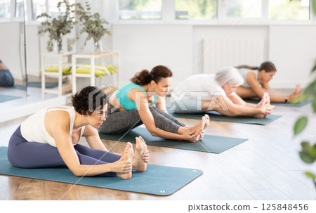 Adult woman doing yoga in group in studio Adult woman doing yoga in group in studio 125848456