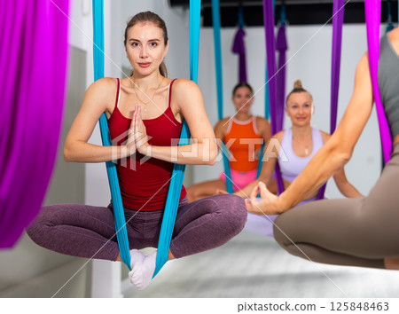 Aerial yoga in hammock. Slim woman performs gravity fly yoga and stretching exercises 125848463