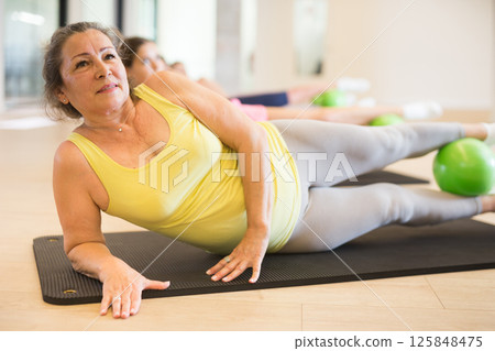 Women practicing pilates with balls at group class in yoga studio Women practicing pilates with balls at group class in yoga studio 125848475