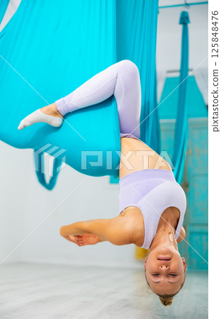 Athletic women hanging upside down in hammock. Fly yoga Athletic women hanging upside down in hammock. Fly yoga 125848476