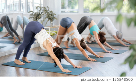 Woman doing downward facing dog pose at group yoga training 125848500