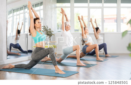 Woman performing Low Lunge Pose at group yoga session Woman performing Low Lunge Pose at group yoga session 125848501