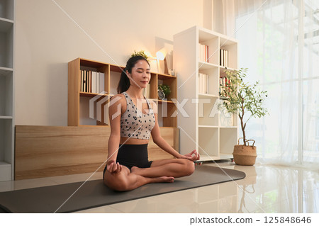 Young woman practicing yoga and mindfulness meditation in a serene home Young woman practicing yoga and mindfulness meditation in a serene home 125848646