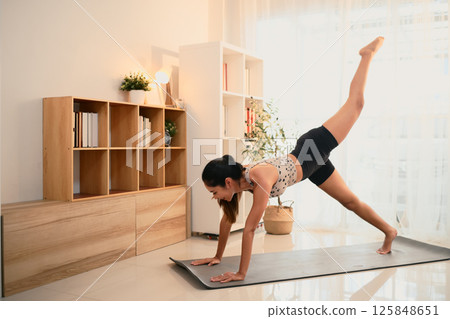 Sporty young asian woman practices yoga in a bright home studio 125848651