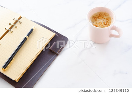 Image of a man working at his desk with a system organizer while drinking a cafe latte, a coffee with plenty of milk Image of a man working at his desk with a system organizer while drinking a cafe latte, a coffee with plenty of milk 125849110