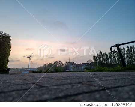 A serene landscape with a wind turbine at sunrise, capturing natures beauty and charm 125849342