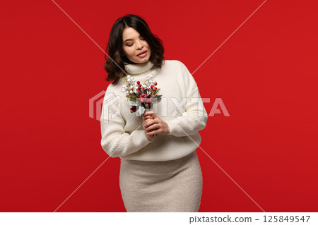 Woman in winter outfit posing with holiday bouquet. 125849547