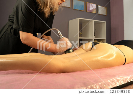 Gloved specialist performs body shaping with RF device on client. 125849558