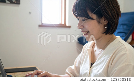 A woman who operates a personal computer at home 125850518