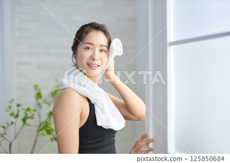 一名二十多歲的女子穿著瑜珈服，用毛巾擦汗 125850684