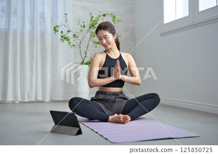 一位二十多歲的女性正在享受線上瑜伽 125850725