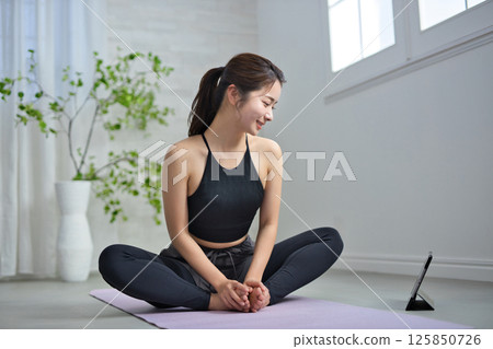 一位二十多歲的女性正在享受線上瑜伽 125850726