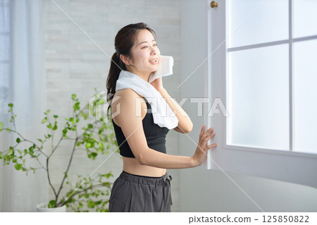 A woman in her twenties wearing yoga wear wiping sweat with a towel 125850822