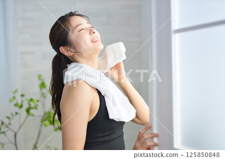 一名二十多歲的女子穿著瑜珈服,用毛巾擦汗 一名二十多歲的女子穿著瑜珈服,用毛巾擦汗 125850848