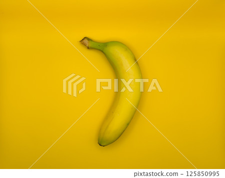 Fresh bright yellow banana on yellow background in the center of the image, top view 125850995