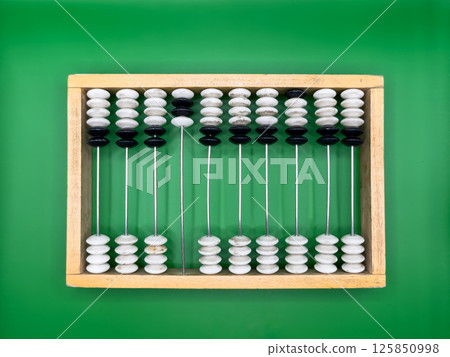 Russian old wooden abacus made of black and white pebbles and beige frame on dark green background in the center top view Russian old wooden abacus made of black and white pebbles and beige frame on dark green background in the center top view 125850998