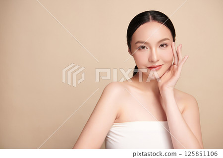 A beautiful young Asian woman with clean, fresh skin against a beige background. Skincare, facial treatment, cosmetology, beauty, and spa. An elegant portrait of an Asian woman. A beautiful young Asian woman with clean, fresh skin against a beige background. Skincare, facial treatment, cosmetology, beauty, and spa. An elegant portrait of an Asian woman. 125851106