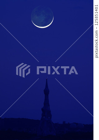 A thin moon floating in the night sky and the Subaru PL Peace Tower 125851401