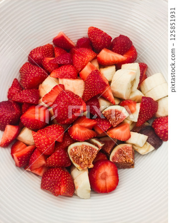 Freshly cut strawberries and bananas arranged in a decorative bowl showcasing colorful fruit medley for healthy eating 125851931