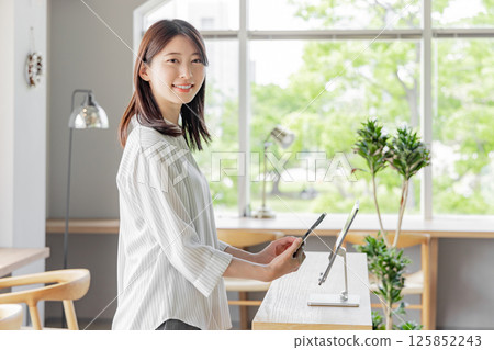 Young woman at hotel reception, tablet, self check-in 125852243