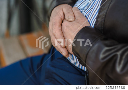 The old man's wrinkled hands are intertwined. The old man's shabby fingers, marked by time. The old man's wrinkled hands are intertwined. The old man's shabby fingers, marked by time. 125852588