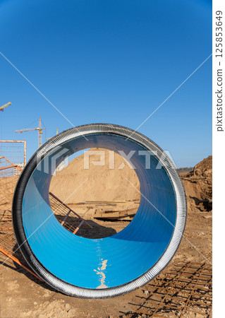 A piece of large corrugated black plastic pipe on construction site. A piece of large corrugated black plastic pipe on construction site. 125853649