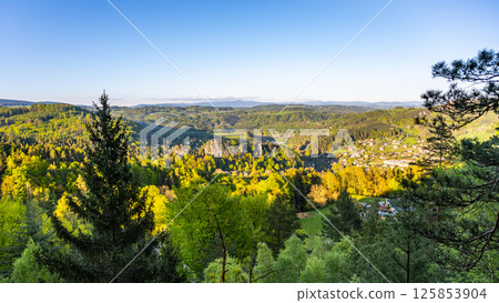 Enjoy breathtaking sights from Pantheon Lookout in Bohemian Paradise, with lush greenery and Krkonose Mountains creating a stunning backdrop at sunset. 125853904