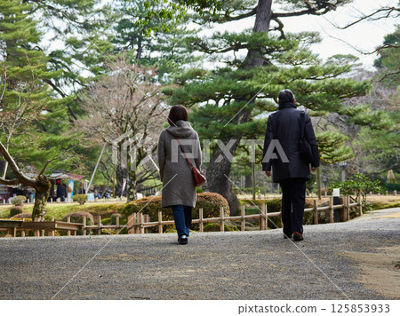 Male and female tourists walking in Kenrokuen Garden in winter 125853933