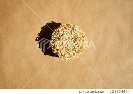 Round block of dry instant noodles over brown background 125854404