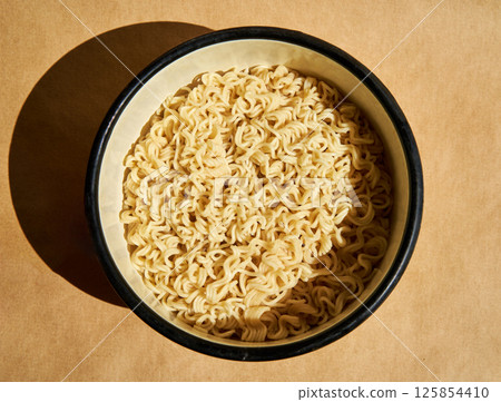 Cooked instant noodles served on ceramic plate over brown background 125854410