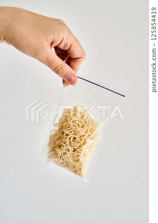 Hand holding ziplock bag with cooked instant noodles inside 125854419