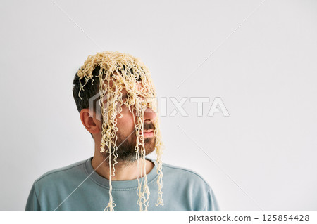 Funny man with cooked instant noodles on head Funny man with cooked instant noodles on head 125854428