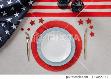 American dinner or table setting for USA Independence Day. Festive dinner with empty white plate and decoration in USA national flag colors red and blue. View from above. Copy space. American dinner or table setting for USA Independence Day. Festive dinner with empty white plate and decoration in USA national flag colors red and blue. View from above. Copy space. 125855147