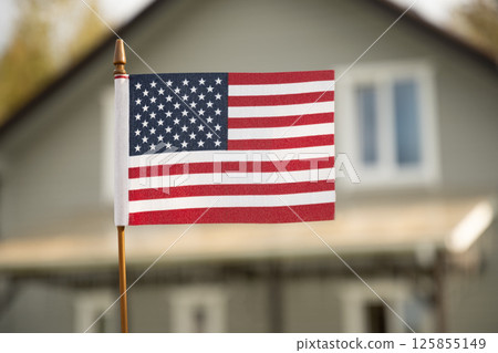 American flag in front of suburban house. American Independence Day patriotic decoration. Freedom and national pride in summer. Outdoors American flag in front of suburban house. American Independence Day patriotic decoration. Freedom and national pride in summer. Outdoors 125855149