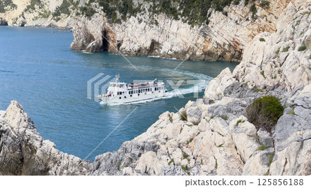 Tourist boat with passengers in bay of Porto Venere, Liguria. Tourists on sea transportation in Italy. Background for design. Tourist boat with passengers in bay of Porto Venere, Liguria. Tourists on sea transportation in Italy. Background for design. 125856188
