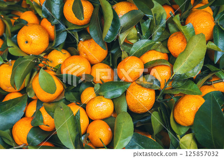 Background with ripe fresh orange tangerines on a market stall. Harvest of fresh citrus fruits Background with ripe fresh orange tangerines on a market stall. Harvest of fresh citrus fruits 125857032