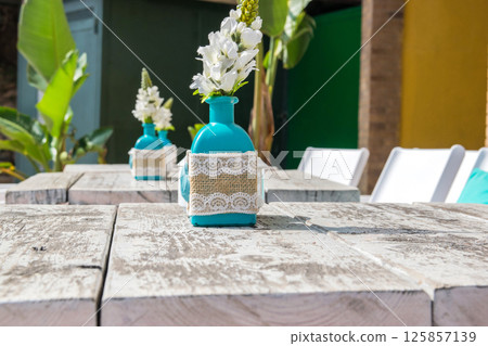 Warehouse on the open air. Chairs and tables outside on the summer sun weather. Vase with the flowers on the table for summer cafe. 125857139