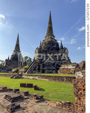 Wat Chaiwatthanaram Ayutthaya temple seen from river boat, ancient famous brick towers under a golden sunset. Traditional heritage, culture. Amazing majestic religious structure. Wat Chaiwatthanaram Ayutthaya temple seen from river boat, ancient famous brick towers under a golden sunset. Traditional heritage, culture. Amazing majestic religious structure. 125857239