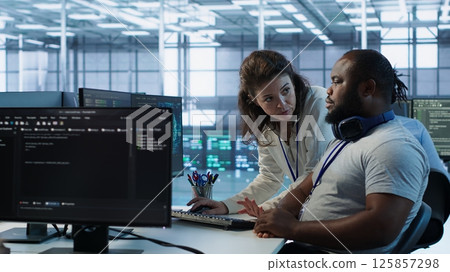 Manager showing admin how to finish tasks in data center providing resources for different workloads. Team leader teaching IT specialist how to while monitor AI supercomputers, camera A Manager showing admin how to finish tasks in data center providing resources for different workloads. Team leader teaching IT specialist how to while monitor AI supercomputers, camera A 125857298