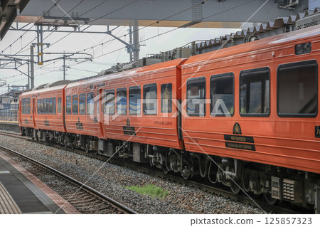 March 26 2025 Vibrant Orange Passenger Train at a Rural Railway Station, Japan March 26 2025 Vibrant Orange Passenger Train at a Rural Railway Station, Japan 125857323