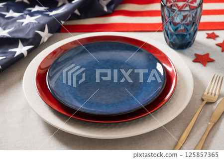 Table setting for USA Independence Day. Festive dinner with empty blue plate and decoration in USA national flag colors. Happy Patriotic Day. Close up. Copy space. 125857365