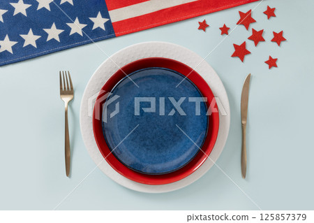 Patriotic table setting for USA Independence Day. Festive dinner with empty white plate and decoration in USA national flag colors white, red and blue. View from above. Copy space. Patriotic table setting for USA Independence Day. Festive dinner with empty white plate and decoration in USA national flag colors white, red and blue. View from above. Copy space. 125857379