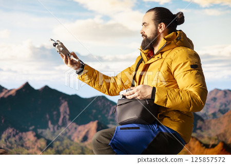 Content creator enjoying the fresh air and filming with his drone, recording professional video on mountain range valley aerial view. Influencer filming his latest travel vlog. Content creator enjoying the fresh air and filming with his drone, recording professional video on mountain range valley aerial view. Influencer filming his latest travel vlog. 125857572