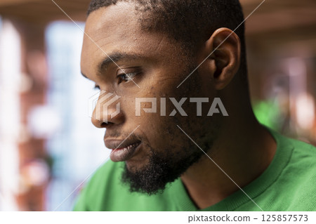 Man having detached apathy facial expression while at home, not caring. Apathetic African american having disinterested indifferent mood while in apartment, close up shot Man having detached apathy facial expression while at home, not caring. Apathetic African american having disinterested indifferent mood while in apartment, close up shot 125857573