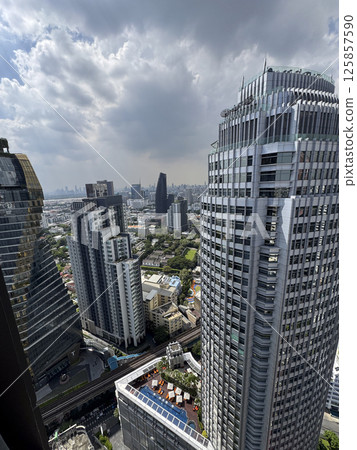 Skyscrapers towering over the Bangkok metropolis with big windows in the city center, corporate area with breathtaking engineering and infrastructure. Urban landscape in Thailand. Skyscrapers towering over the Bangkok metropolis with big windows in the city center, corporate area with breathtaking engineering and infrastructure. Urban landscape in Thailand. 125857590